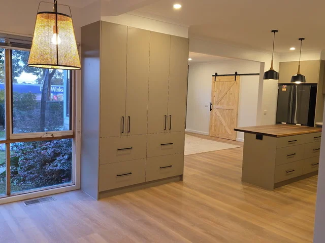 Renovated open-plan kitchen with full-height custom joinery and a sliding barn door
