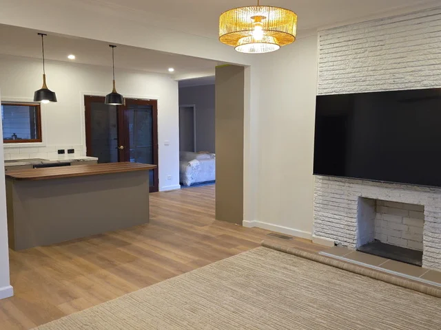 Renovated open-plan living area with a white brick fireplace feature wall